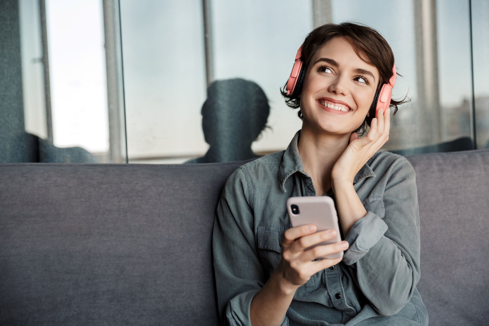 Woman in headphones smiling and holding phone